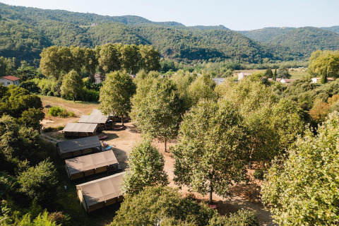 Vista aerea delle tende safari Villatent Nomad al Camping La Garenne in Francia, immerse tra alberi e colline.