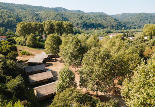Vista aerea delle tende safari Villatent Nomad al Camping La Garenne in Francia, immerse tra alberi e colline.