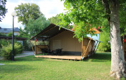Tienda safari con instalaciones sanitarias en Camping Vallee de L'Our, Luxemburgo, rodeada de vegetación.