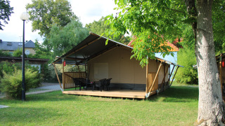 Tenda safari con servizi igienici al Camping Vallee de L'Our in Lussemburgo, circondata dal verde.