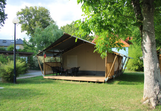 Tienda safari con instalaciones sanitarias en Camping Vallee de L'Our, Luxemburgo, rodeada de vegetación.