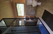 Bagno in una tenda safari lodge con doccia, WC, finestra e mobili in legno.