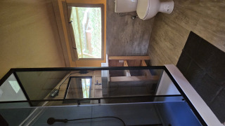 Badkamer in een safaritent lodge met douche, toilet, raam en houten meubels.