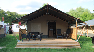 Safari tent with wooden deck and outdoor seating at Camping Vallee de L'Our in Luxembourg, exterior view.
