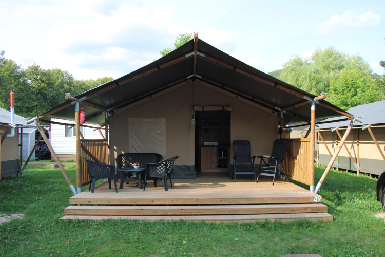 Safari tent with wooden deck and outdoor seating at Camping Vallee de L'Our in Luxembourg, exterior view.