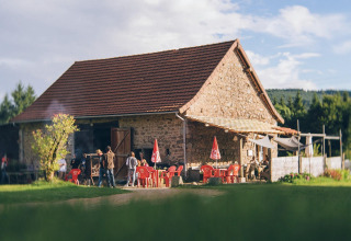 Stenhus med rødt tag og røde stole foran, feriepark i Auvergne-Rhône-Alpes, Frankrig, solrig dag