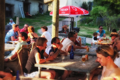 Personas disfrutando bebidas y conversación al aire libre en Camping Domaine La Chabanne en Francia.
