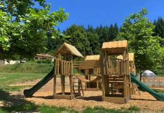 Parco giochi in legno con scivoli e strutture da arrampicata a Camping Domaine La Chabanne in Francia.