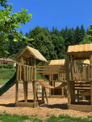 Parque infantil de madera con toboganes y estructuras para trepar en Camping Domaine La Chabanne, Francia.