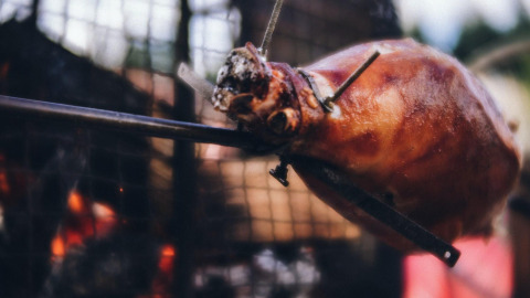 Primo piano di un agnello intero arrosto allo spiedo su fuoco al Camping Domaine La Chabanne, Auvergne-Rhône-Alpes, Francia.