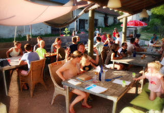 Udendørs fællesområde på Camping Domaine La Chabanne, fyldt med familier og børn i solskin.