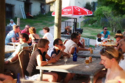 Huéspedes disfrutan de una comida y bebida al aire libre en Camping Domaine La Chabanne, Francia.