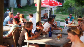 Huéspedes disfrutan de una comida y bebida al aire libre en Camping Domaine La Chabanne, Francia.