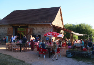 Udendørs familiesammenkomst ved Camping Domaine La Chabanne med mange mennesker foran en rustik bygning.