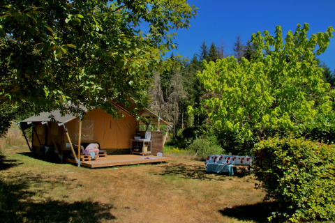 Safari telt Greenlodge ved Camping Domaine La Chabanne i Frankrig, omgivet af træer på en solrig dag.