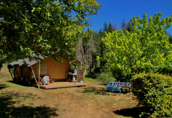 Safari tent Greenlodge at Camping Domaine La Chabanne in France, surrounded by trees and sunny nature.