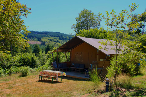 Tienda safari Greenlodge en el Camping Domaine La Chabanne en Francia, rodeada de naturaleza y montañas verdes.