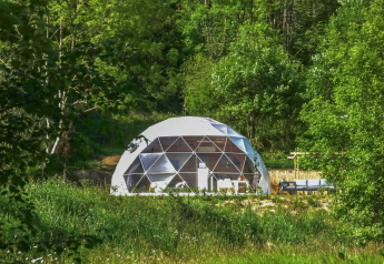 Cupola geodetica al Camping Domaine La Chabanne in Francia, circondata da verde e alberi rigogliosi.