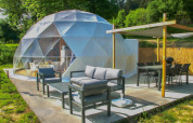 Área de descanso exterior junto a la cúpula en Camping Domaine La Chabanne en Francia, con muebles modernos y naturaleza.