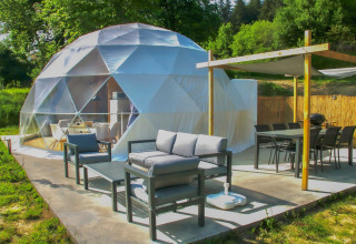Área de descanso exterior junto a la cúpula en Camping Domaine La Chabanne en Francia, con muebles modernos y naturaleza.