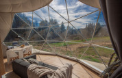 Vista interior de una cúpula en Camping Domaine La Chabanne en Francia con paredes de vidrio y paisaje natural.