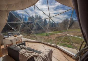 Vista interna di una cupola al Camping Domaine La Chabanne in Francia con pareti di vetro e natura.