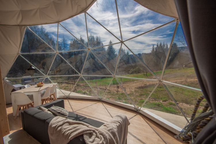 Vista interior de una cúpula en Camping Domaine La Chabanne en Francia con paredes de vidrio y paisaje natural.
