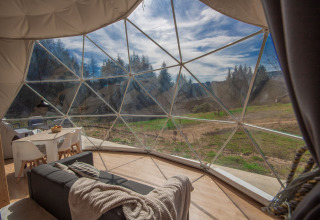 Vista interior de una cúpula en Camping Domaine La Chabanne en Francia con paredes de vidrio y paisaje natural.