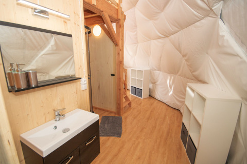 Binnenkant van de Dome bij Camping Domaine La Chabanne, Frankrijk, met lavabo, trap en witte opbergkasten.