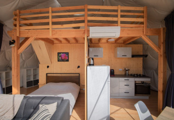 Interior view of a dome at Camping Domaine La Chabanne in France, featuring a loft and a modern kitchen.