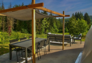 Terraza exterior en el Dome de Camping Domaine La Chabanne en Francia, rodeada de naturaleza y bosques verdes.