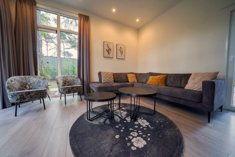 Stylish living room at Cube la Mer, De Zanding, Netherlands, featuring sofa, armchairs, tables and garden view.