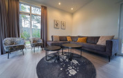 Modernes Wohnzimmer in Cube la Mer, De Zanding, Niederlande, mit Sofa, Sesseln und Gartenblick.