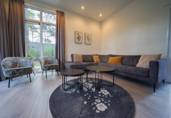 Moderne woonkamer in Cube la Mer, De Zanding, Nederland, met hoekzetel, stoelen, tafels en zicht op tuin.