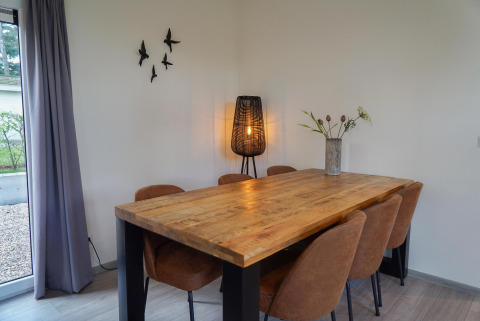 Salle à manger de Cube la Mer à De Zanding, Pays-Bas, avec table en bois, six chaises, lampe et décoration murale.
