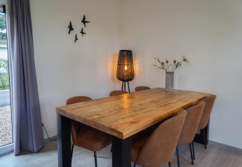 Eethoek in Cube la Mer bij De Zanding, Nederland, met houten tafel, zes stoelen, lamp en muurdecoratie.