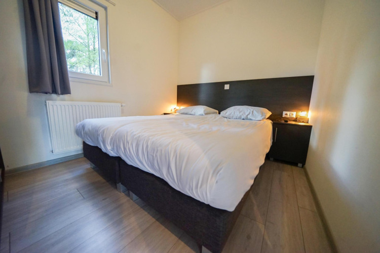 Schlafzimmer mit Doppelbett, moderner Einrichtung und sanfter Beleuchtung in Cube la Mer, De Zanding, Niederlande.