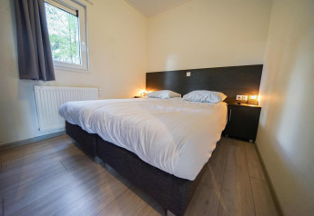 Chambre avec lit double, mobilier moderne et lumière douce à Cube la Mer, De Zanding, Pays-Bas.