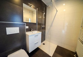 Modern bathroom with walk-in shower, sink cabinet, and wall mirror at Cube la Mer, De Zanding, Netherlands.
