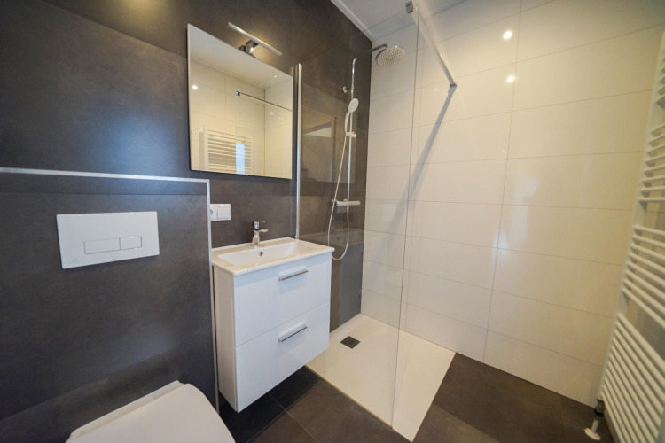 Baño moderno con ducha, lavabo con cajones y espejo en Cube la Mer, De Zanding, Países Bajos.