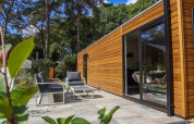 Zona exterior con muebles modernos en Wellness Lodge De Zanding, Países Bajos, junto a fachada de madera.