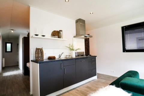 Modern kitchen area in Wellness Lodge at De Zanding, Netherlands, featuring sleek black cabinets and light.