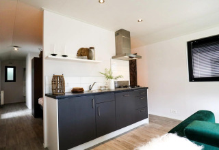 Moderne keukenhoek in de Wellness Lodge bij De Zanding, Nederland, met zwarte kasten en natuurlijke lichtinval.