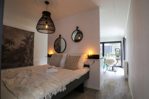 Dormitorio moderno en Wellness Lodge de De Zanding, Países Bajos, con iluminación cálida y decoración elegante.