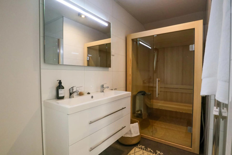Baño moderno con sauna, lavabo doble y espejo en Wellness Lodge en De Zanding, Países Bajos.