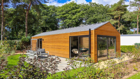 Wellness Lodge bij De Zanding in Nederland met moderne houten buitenkant, grote ramen en tuinterras.