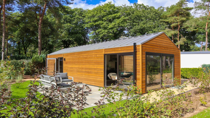 Wellness Lodge en De Zanding, Países Bajos, con fachada de madera moderna, grandes ventanales y jardín.