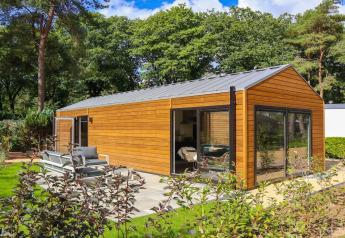 Wellness Lodge en De Zanding, Países Bajos, con fachada de madera moderna, grandes ventanales y jardín.