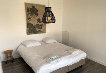 Modernes Lodgezimmer im Mode Sauna bei De Zanding, Niederlande, mit Doppelbett, Holzstuhl und schlichter Dekoration.
