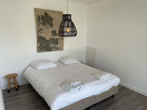 Modernes Lodgezimmer im Mode Sauna bei De Zanding, Niederlande, mit Doppelbett, Holzstuhl und schlichter Dekoration.